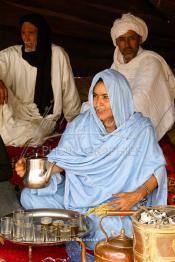 Image du Maroc Professionnelle de  Une Sahraouiya (femme marocaine du désert) verse  le thé aux hommes et aux invités, sous la tente familiale, Samedi 18 septembre 2004, la cérémonie a lieu dans un site désertique sur lequel la ville de Tan Tan, a toujours accueilli la majorité des tribus et des grandes familles nomades du désert lors d'un grand Moussem, danse, chants, course de chameaux et fantasia font partie des festivités. ((Photo / Abdeljalil Bounhar)








